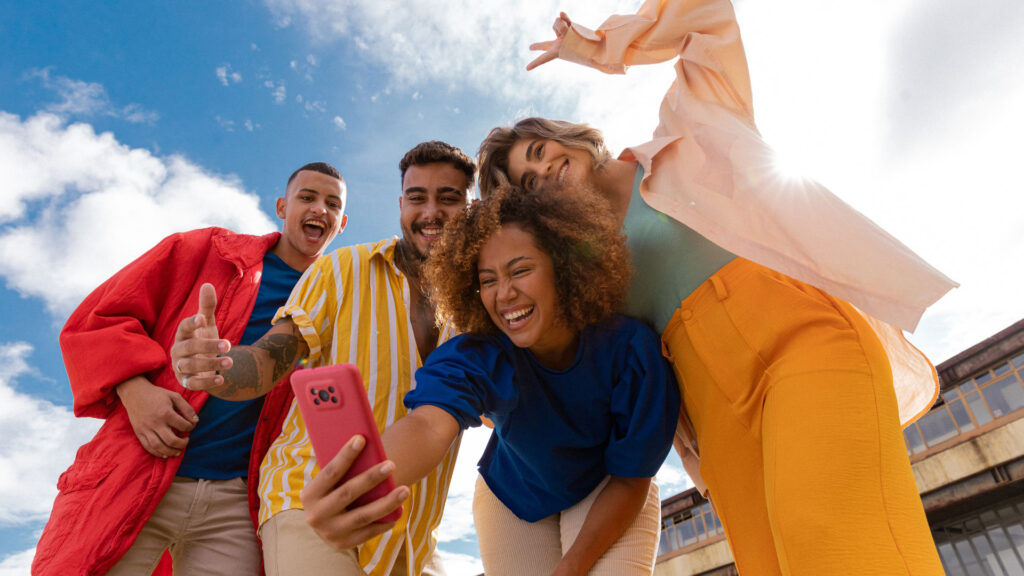 A photo of four young people taking a high energy seflie.